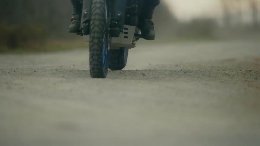 A cyclist is riding a motorcycle on a rural road