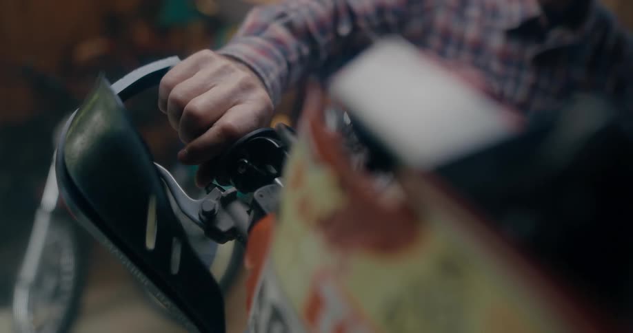 Man twisting a motorcycle throttle parked inside a warehouse