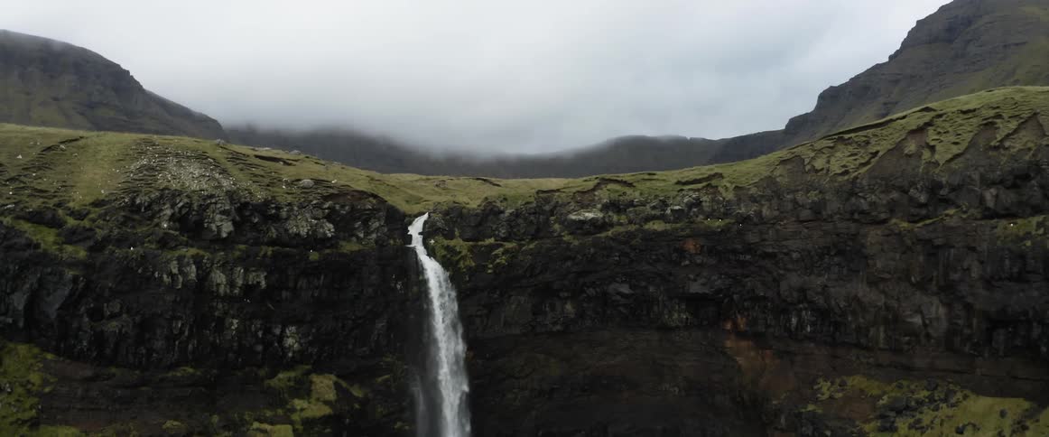 River flows past valley and flows down cliff into ocean