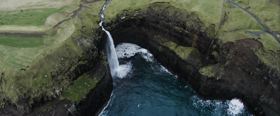 River water flows off the cliffs splashing into the basin below