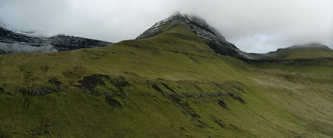 A grassy sloped hill on a cloudy day
