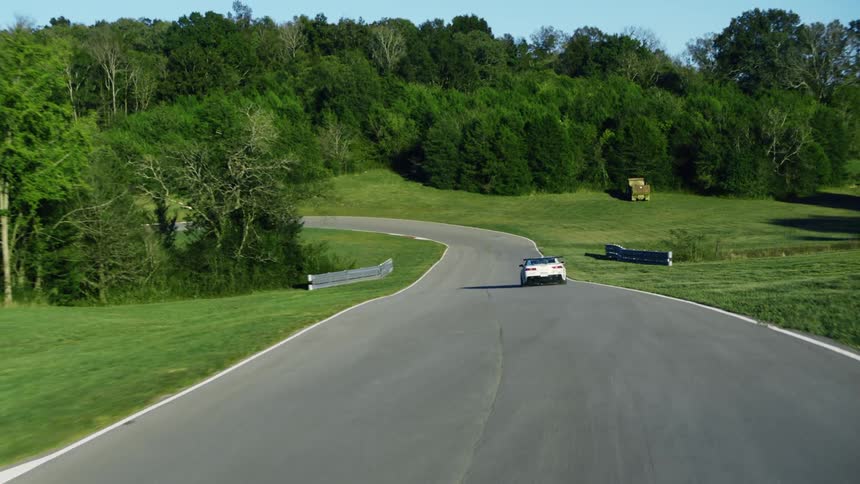 A race car speeding down a road on a summer day