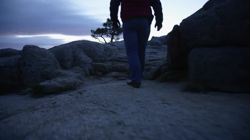 A man walks up a rocky hill