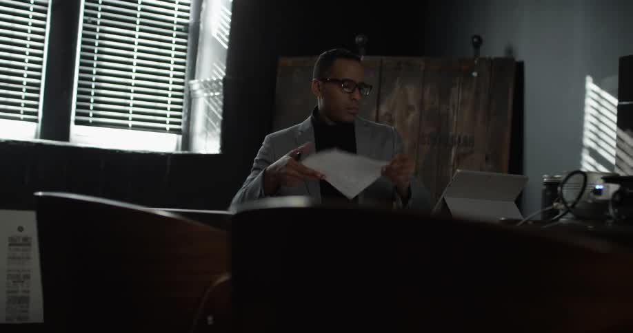 A man in a gray jacket works at a desk