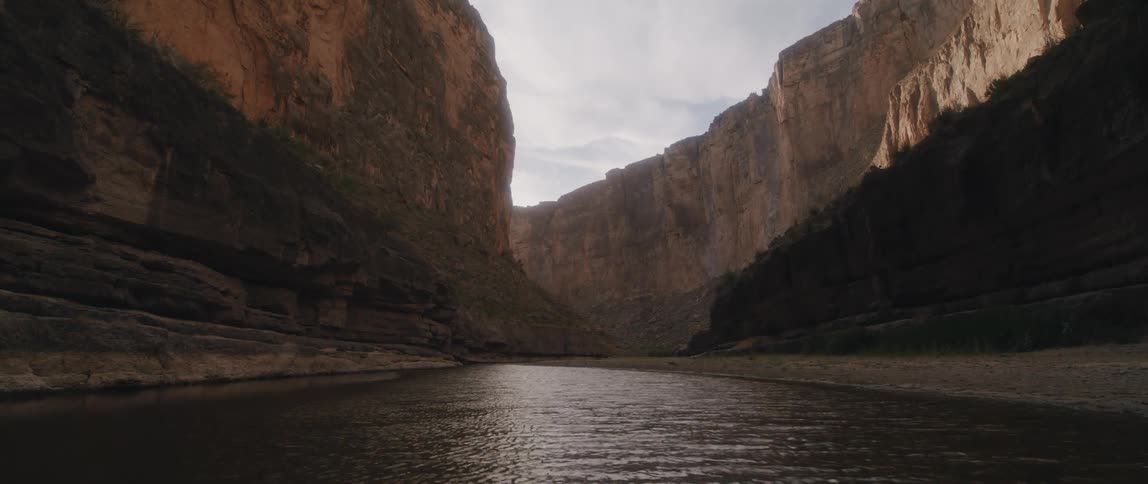 River flows through canyon under cloudy sky