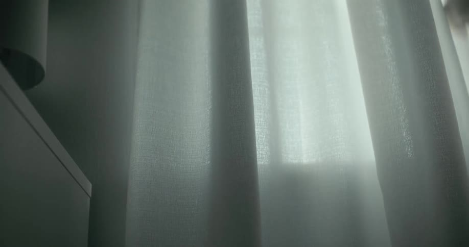 A person closes the drapes on a window indoors