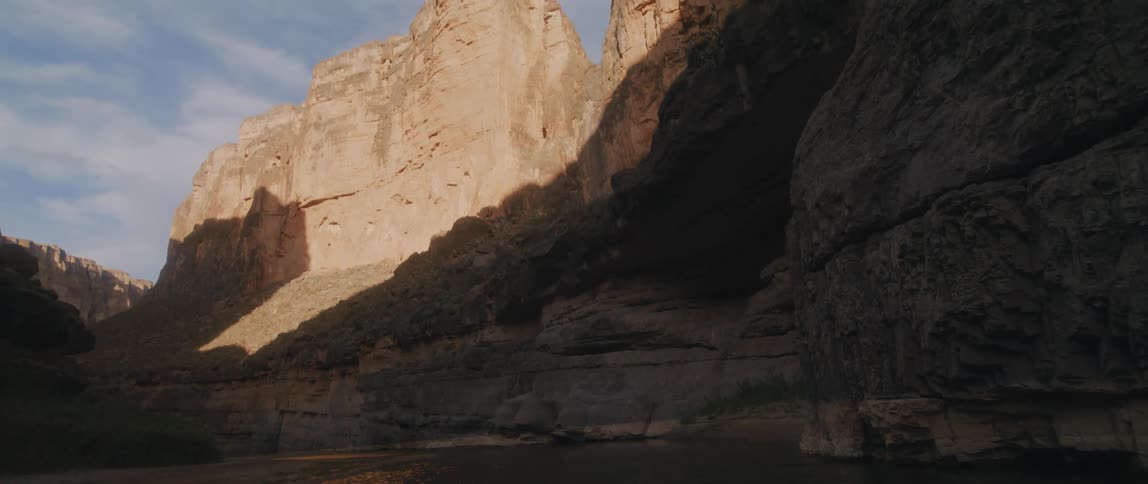 River flowing under the shadow of a mountain range in the desert at morning