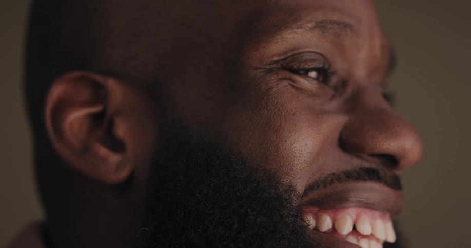 Close up of the face of a bearded man smiling on a room