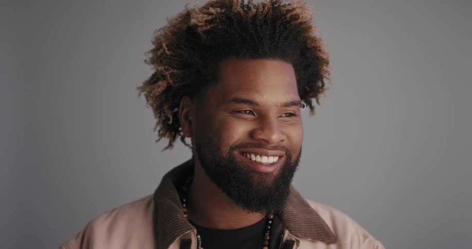 A bearded man smiling for a portrait indoors
