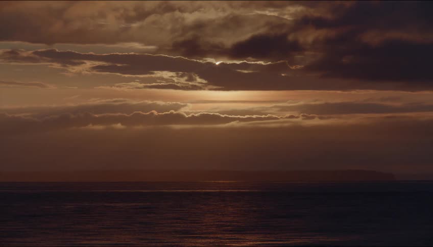 The ocean waves reflect the colors from the orange sky above