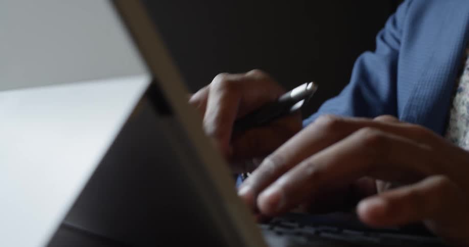 A person in a blue shirt types on a laptop