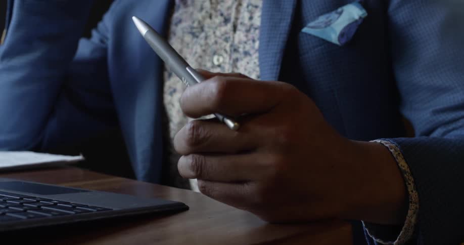 A man talks on a phone as he flips a pen in his hand