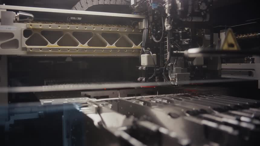 A large metal arm moves inside machinery