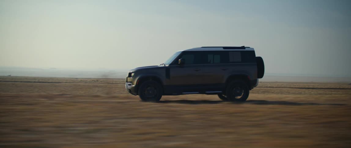 A black truck is traveling on a desert road