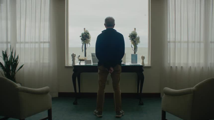 A man stands looking out the window