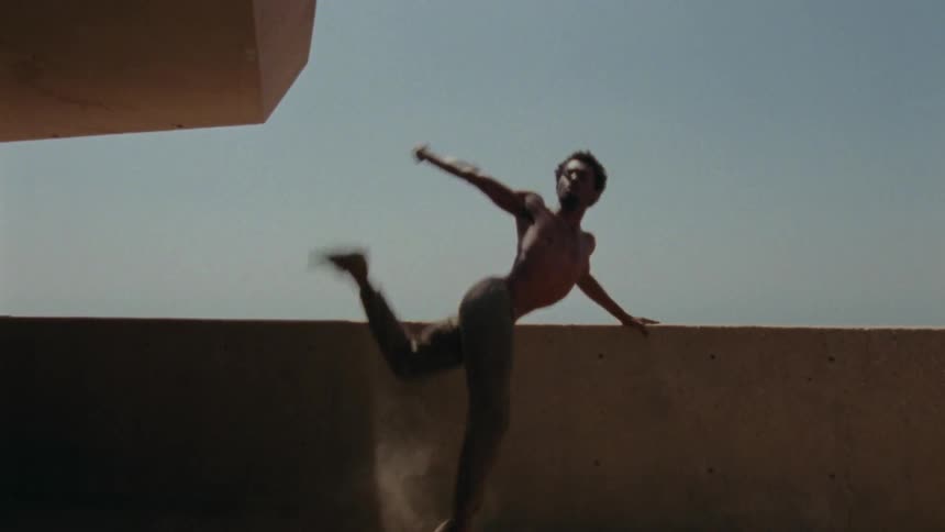 A man is dancing outdoors on a rooftop building