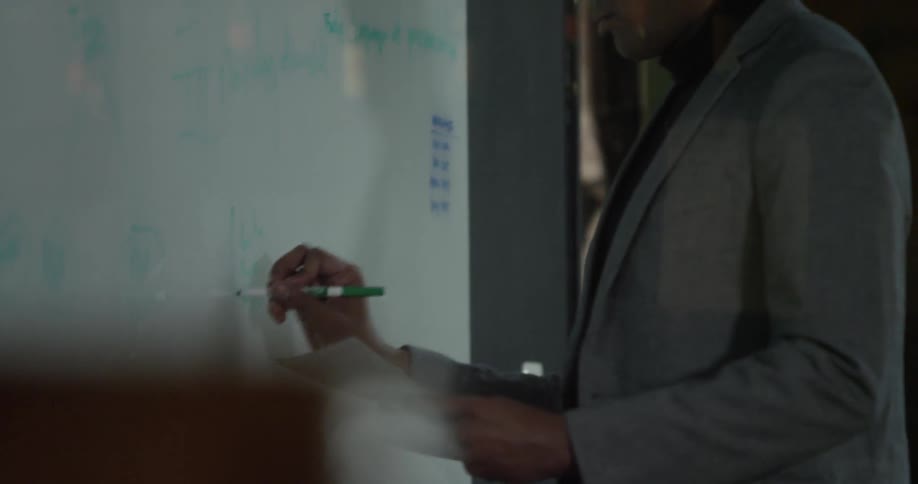 Man writes information from paper onto dry-erase board