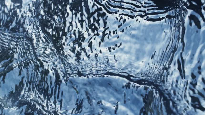 Blue sky reflecting on the rippling surface of a dark shallow river