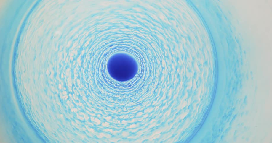 Bright blue ink flowing in concentric circles over white liquid ink