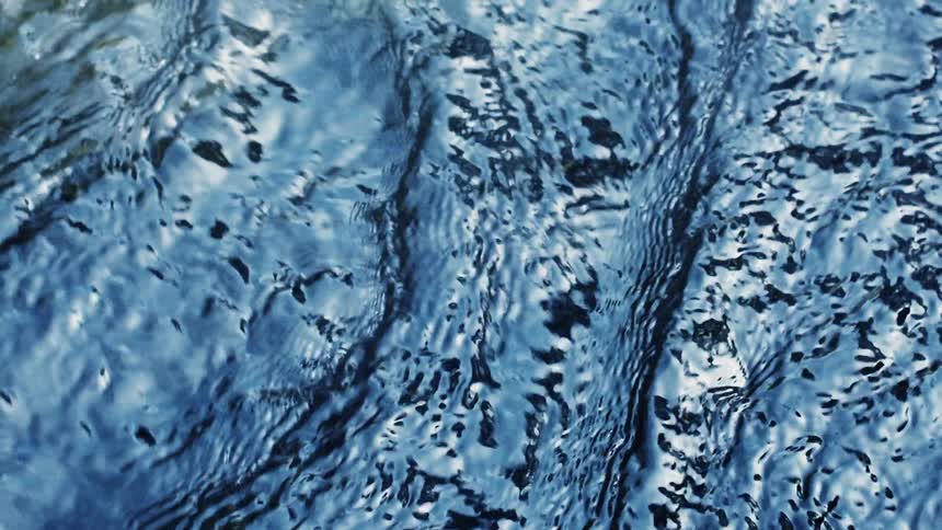 Water flowing and merging with ripples and light reflected on the surface
