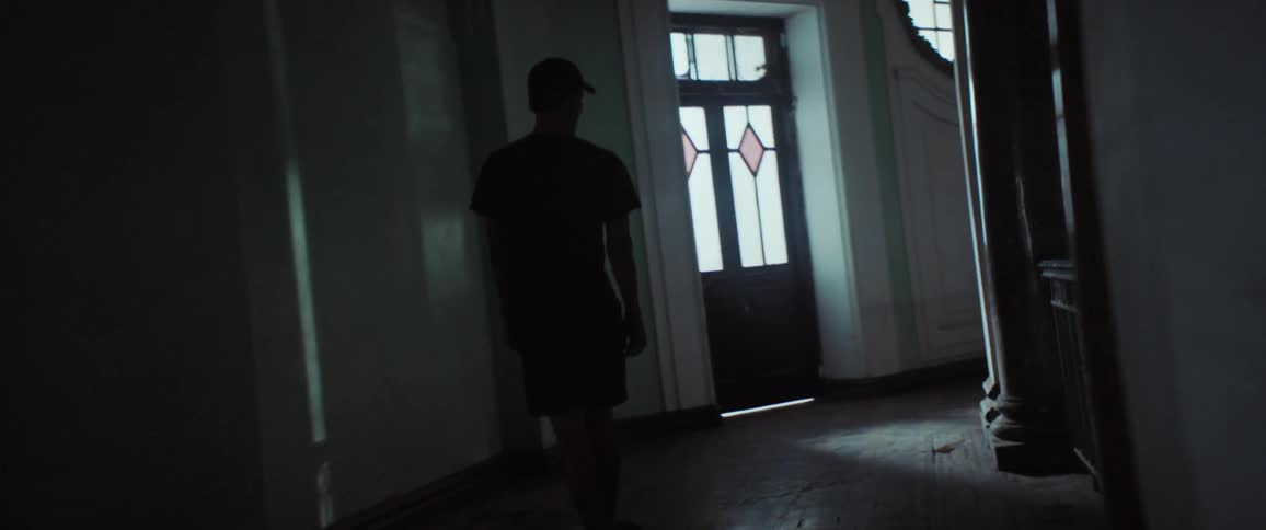 Man rides skateboard along hall bordering open area