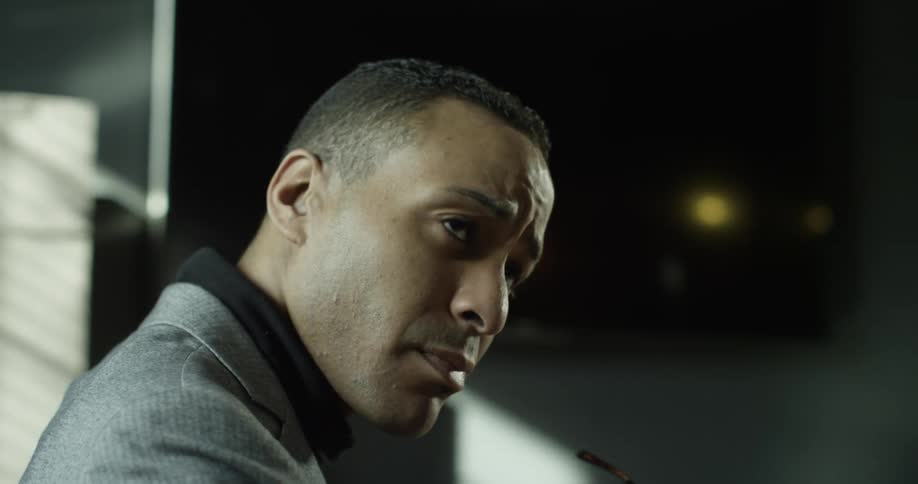 A man removes his glasses and looks over