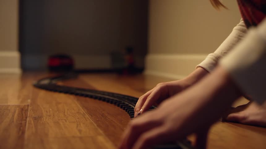 A person is putting together model train tracks