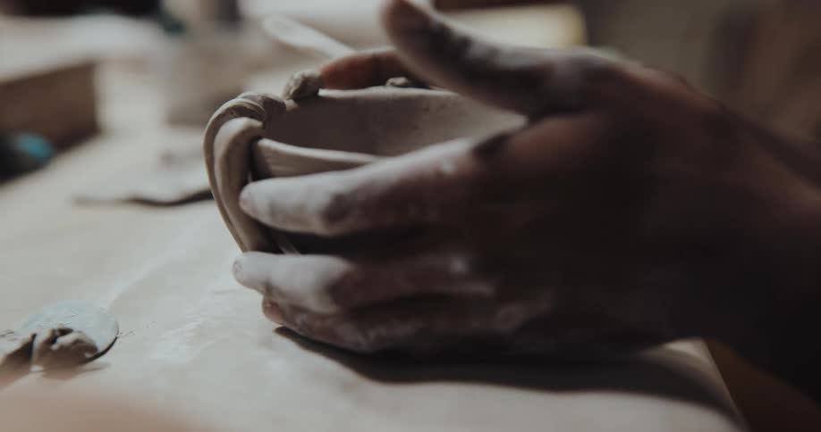 A man is sculpting a cup
