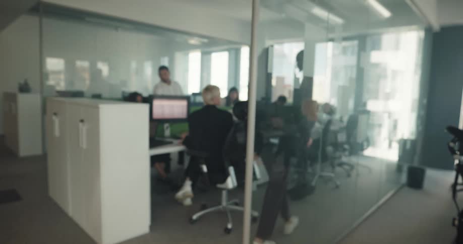 Determined woman enters a busy and active office and sits on her desk