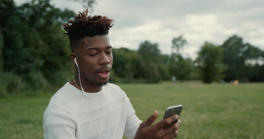 A man sitting outdoors using a smartphone