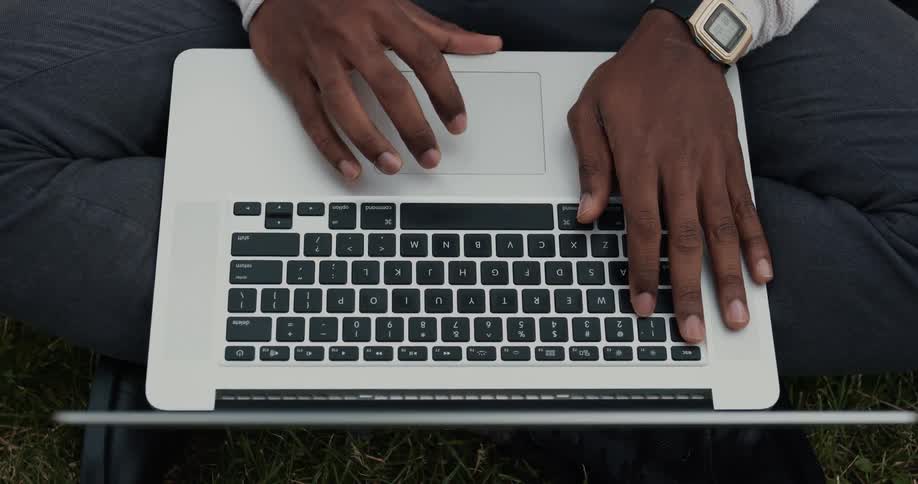 A man is typing on a laptop computer keyboard