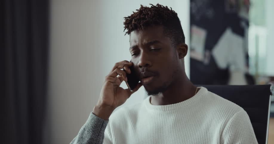 A man is sitting at a table talking on the phone