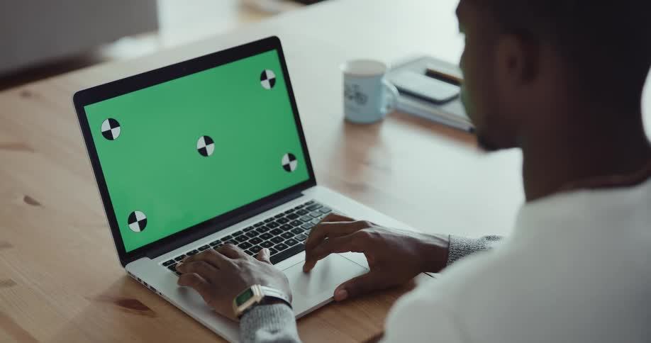 A man is sitting at a table and typing on his laptop