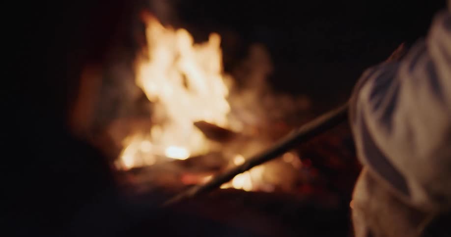 A man is sitting by a bonfire during the night time