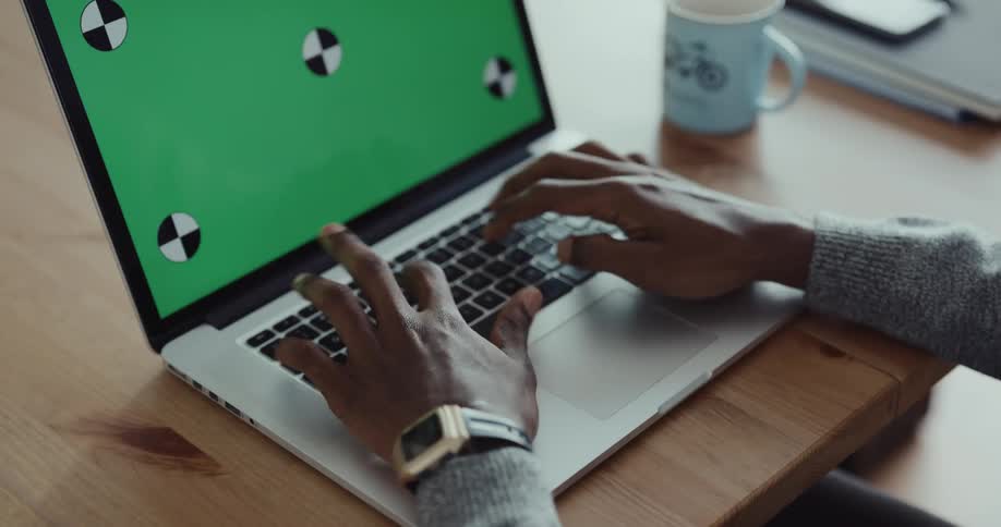 A person is sitting at a desk and typing on a laptop