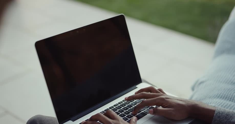 A man is typing on a laptop computer keyboard