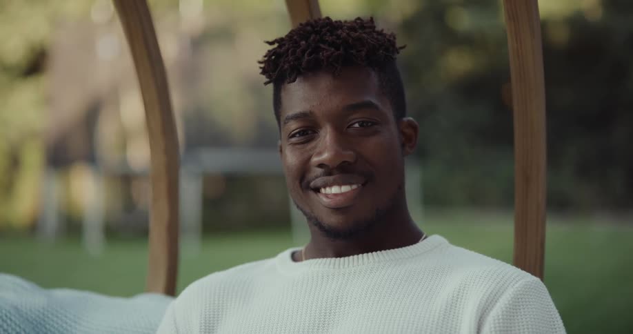 A man is sitting in his backyard and is smiling