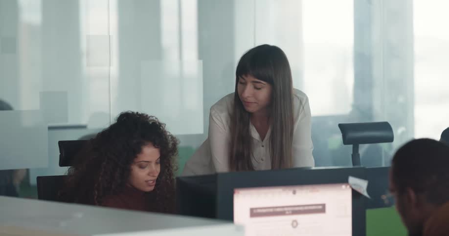 Businesspeople sitting at desks work on computers at the office
