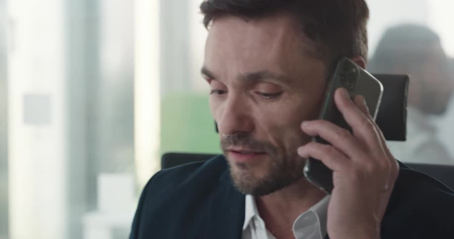 A man is talking on the phone and sitting in his office