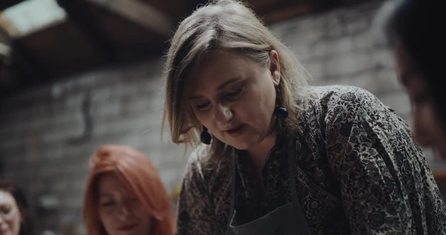 Pottery instructor helps woman shape bowl