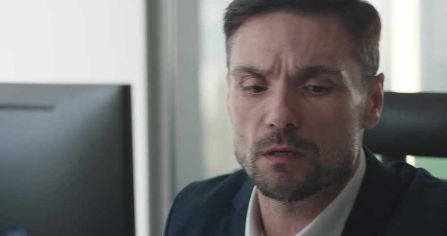 A man is sitting in his office and talking on cellphone