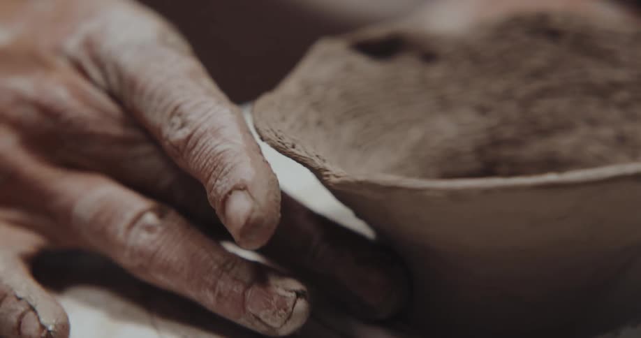 Sculptor shapes a small vase over a turning table