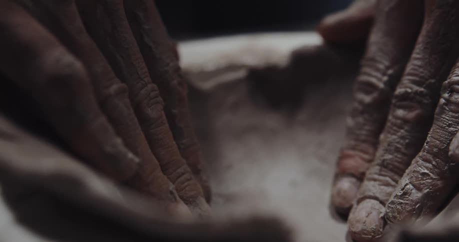 A person is forming clay into a bowl shape