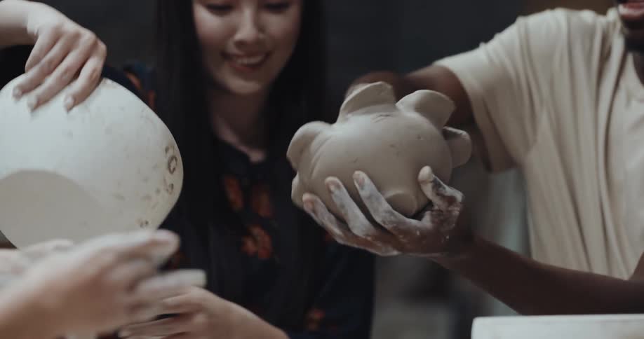 Woman helps man remove clay bowl from larger bowl used to shape it