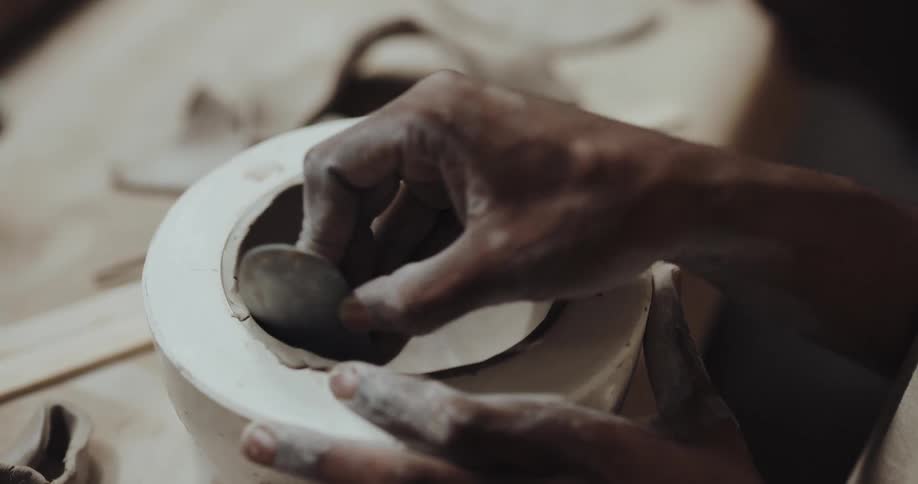 A woman is making a bowl out of clay