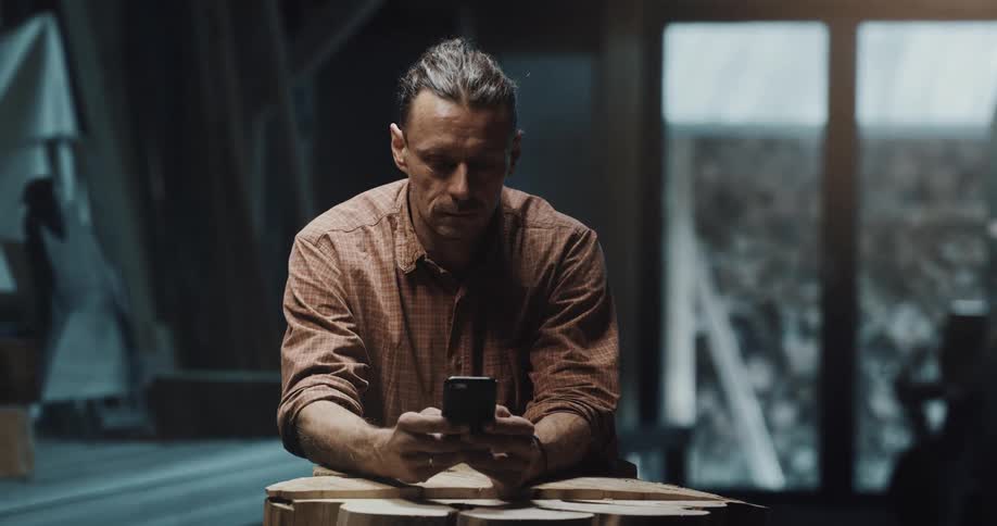A man uses his smartphone while sitting indoors during the day