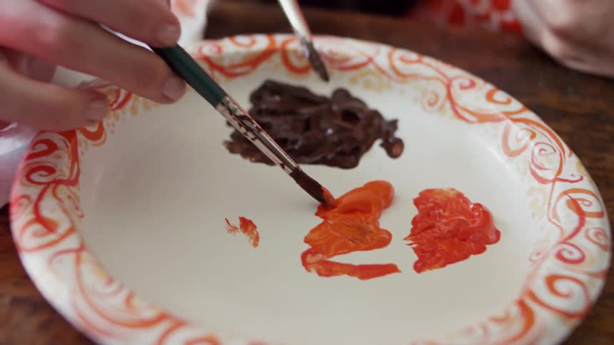 People put paint on their brushes from a paper plate