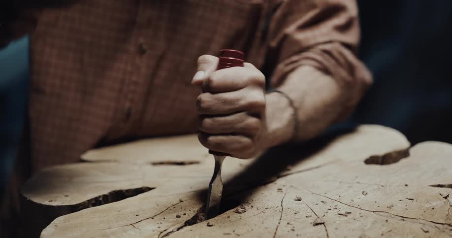 A man is carving into a tree trunk