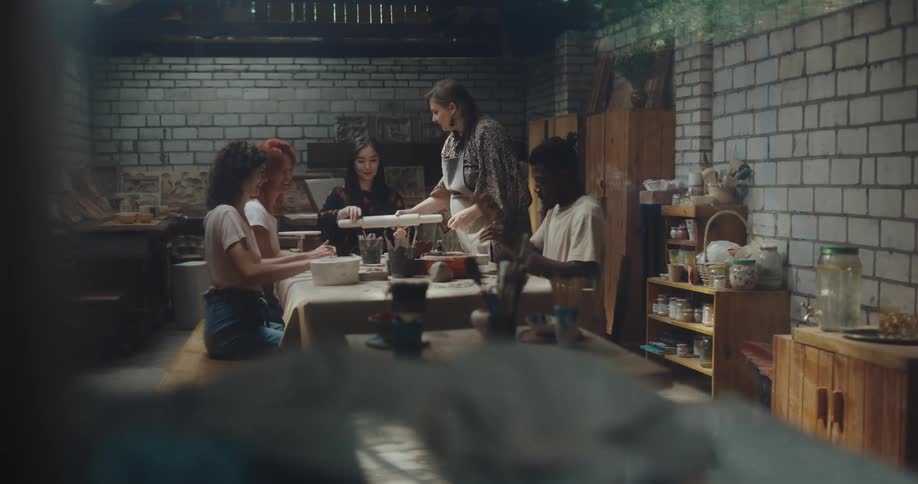 A group of people sit around a table preparing clay for artwork