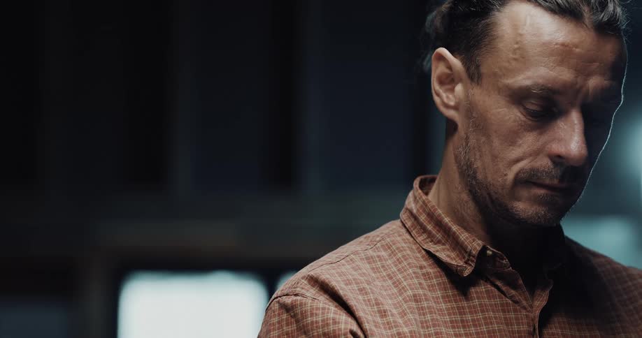 A man is standing in his house and looking down